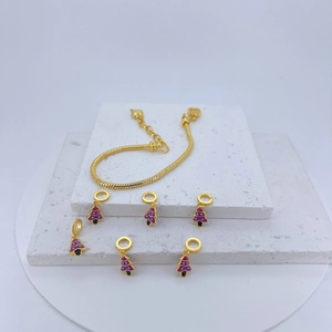 Detail of gold snake chain bracelet with purple enamel Christmas tree charms on stone stand