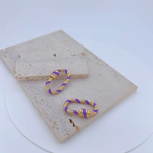 Detailed macro view of purple enamel and gold-plated copper earrings with zircon stones