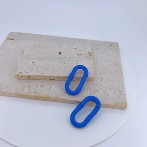 Zwei blaue matte ovale Karabinerhaken auf Travertinstein für DIY-Schmuckzubehör