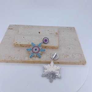 Pendentif flocon de neige détaillé avec pierres de zircon colorées sur fond de pierre
