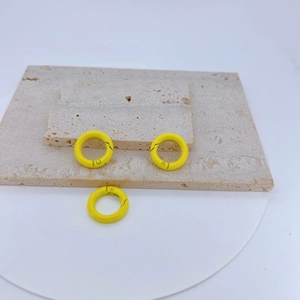 Three bright yellow matte spring O-rings for DIY bags and keychains on stone texture