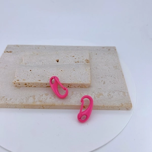 Macro detail of rose pink copper lobster clasps on a natural stone tray for DIY jewelry