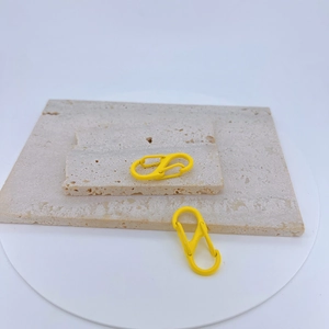 Macro view of a bright yellow S-shaped double carabiner on a textured stone tray
