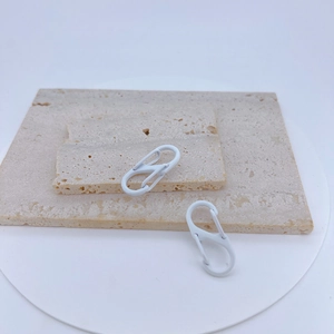 Dual white S-shaped carabiners displayed on stone slabs for backpack and key accessories