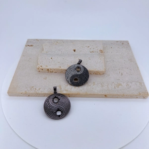 Vue détaillée des pendentifs Yin Yang avec micro-cristaux sur socle en pierre