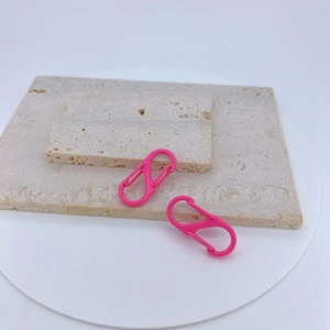 Pink S-Biner dual carabiner hooks with matte finish on a textured stone display surface