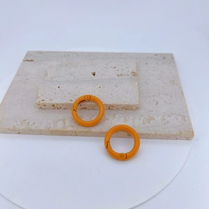 Macro detail of vibrant orange spring ring clasps on elegant stone texture background
