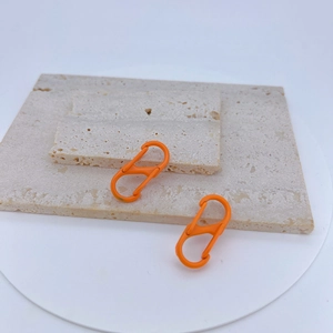 Detail of two bright orange S-shaped carabiners with spring clips on stone travertine
