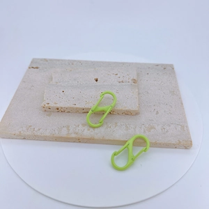 Detail of neon green S-shaped carabiners in matte finish on a stone texture base