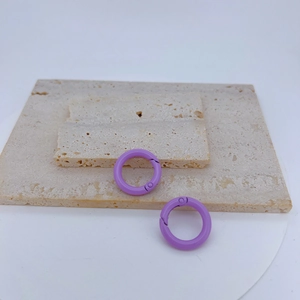 Close-up of two light purple round metal spring ring clasps on a beige stone surface