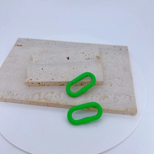 Nahaufnahme von zwei limettengrünen ovalen Federclips auf strukturiertem Stein für DIY-Schmuck