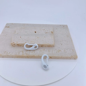 Detail showing white matte spring snap hooks on beige stone texture for DIY crafts