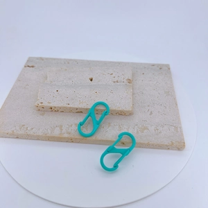 Close-up of dual Tiffany blue S-shaped carabiners on a natural stone textured display