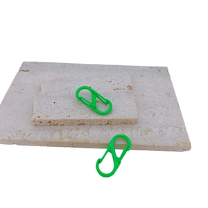 Green S-shaped dual spring carabiner set with matte finish on textured stone display