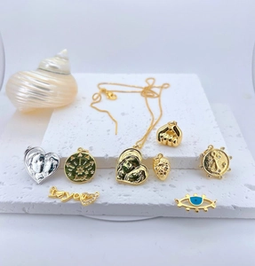 Primer plano de colgantes de latón bañados en oro con motivos de suerte y circonita