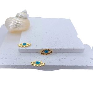 Tres colgantes ojo turco chapados en oro con esmalte azul sobre fondo de piedra blanca