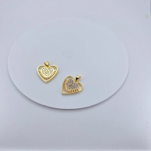Golden heart-shaped pendant with zircons and sunburst pattern on a white tray