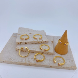 Detailweergave van gouden verstelbare ringen met roze hartstenen en getextureerde banden
