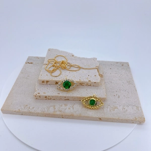 Detail of evil eye pendant with green gemstone on travertine stone display