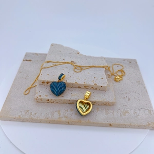 Collier élégant doré avec pendentif cœur pavé de pierres turquoise sur décor minéral