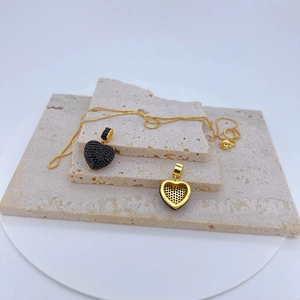 Détail macro du pendentif cœur avec pavé de zircons noirs et structure dorée ajourée