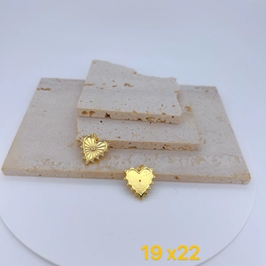 Detalle de dos colgantes de corazón dorados con circonitas sobre piedra natural