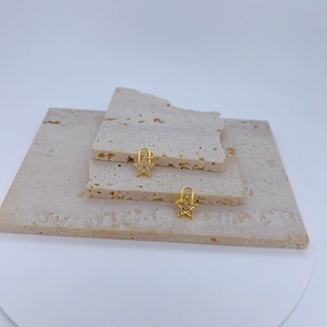 Detail of gold star pendants with micro-pave zircons on beige travertine stone blocks