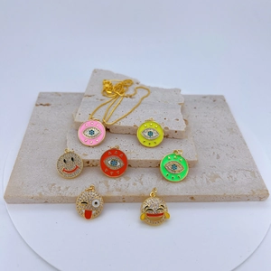 Detailansicht von Evil Eye und Emoji Anhängern mit buntem Emaille auf Steintablett