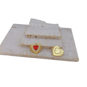 Gothic gold heart pendant with red enamel and white zircon inlay on stone surface