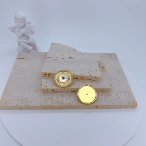 Detail of gold-plated evil eye pendants with zircons on beige travertine stone display