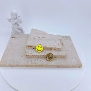 Détail de pendentifs smiley en émail jaune et or texturé pour la création de bijoux