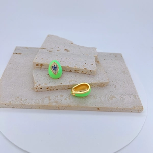 Macro view of gold-plated evil eye charms with neon green enamel and blue zircon stones