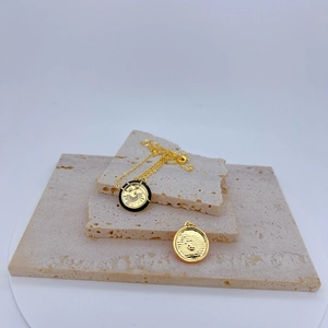 Golden geometric celestial necklace with sun and moon enamel pendant on travertine stone