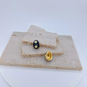 Detail shot of oval evil eye pendants with black enamel and gold plating on stone base