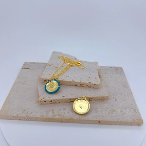 Detail of sun and star relief on gold pendant with blue enamel and crystal inlay