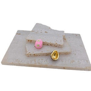 Pink evil eye enamel egg pendant and gold-plated bead on natural stone background