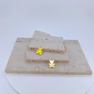 Detailweergave van beervormige gouden hangers met geel emaille en wit hart op steen