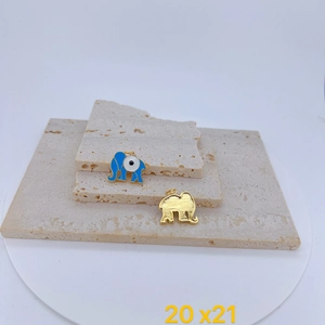 Macro detail of blue enamel elephant charm and gold evil eye pendant on stone surface