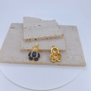 Détail d'un pendentif ours doré avec gemme bleue et zircons, montrant l'avant et l'arrière