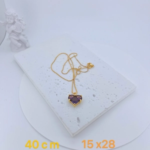 Detail showing a purple heart zircon pendant with gold-plated chain on marble