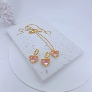 Detail shot of heart-shaped pink zircon jewelry set on white marble with angel decor