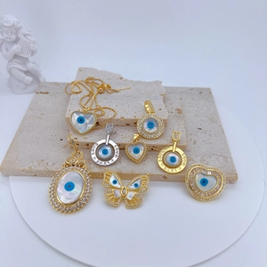 Macro detail of gold-plated evil eye charms with mother of pearl and zircon inlay