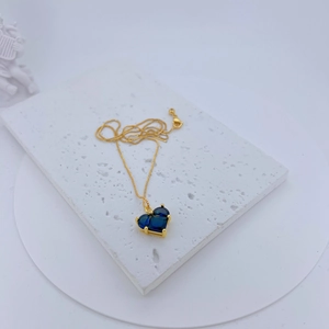 Macro detail of a heart-shaped blue zircon pendant necklace with a gold chain