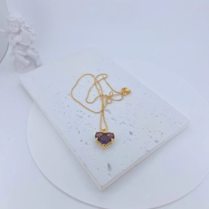 Detail of gold-plated necklace with a heart-shaped purple zircon pendant and fine box chain