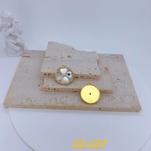 Detailed view of gold-plated clover pendant with white shell and blue evil eye detail