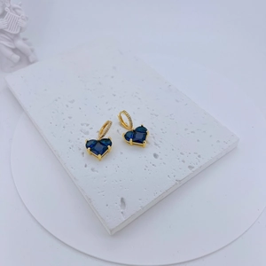 Detail of gold heart earrings with deep blue zircons and micro-pave crystals
