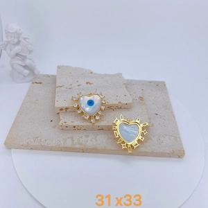 Detailed macro view of heart-shaped gold-plated shell charms with blue devil eye inlays
