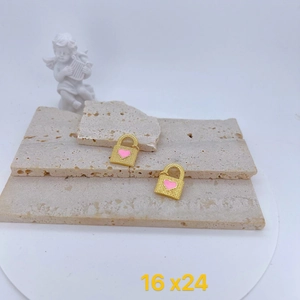 Detail of gold heart lock charms with pink enamel and beaded texture on stone base