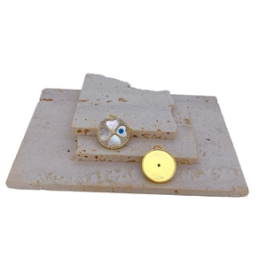 Gold plated clover charm with white shell inlay and blue evil eye detail on stone base
