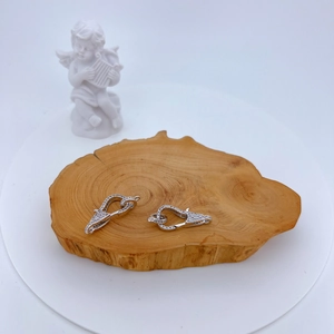 Chiusure a moschettone in argento con zirconi micro-pave su vassoio di legno